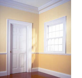 Стая с жълти стени и прозорец и бяла врата с первази