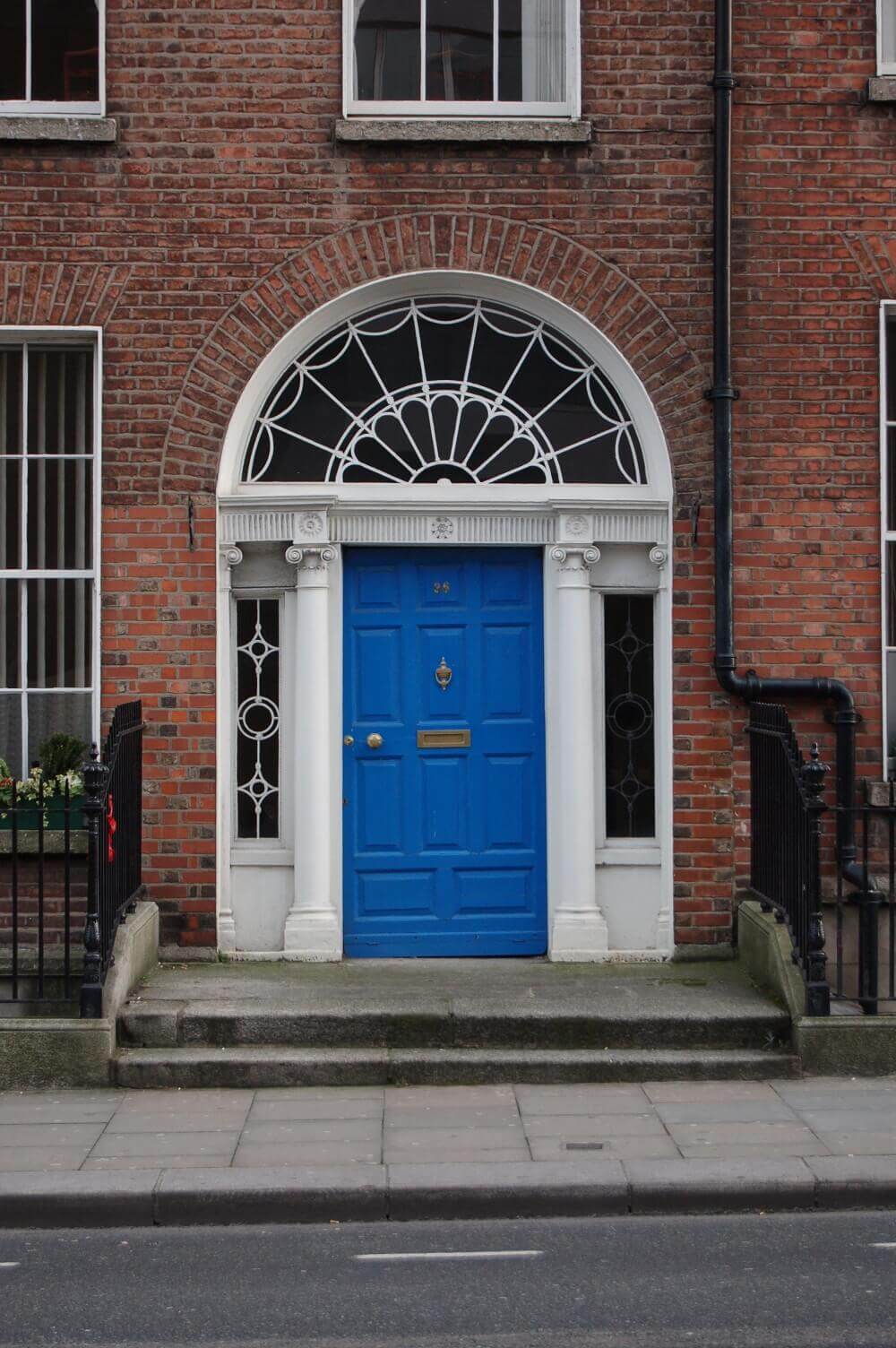 Входна врата в син цвят с овален свод от стъкло